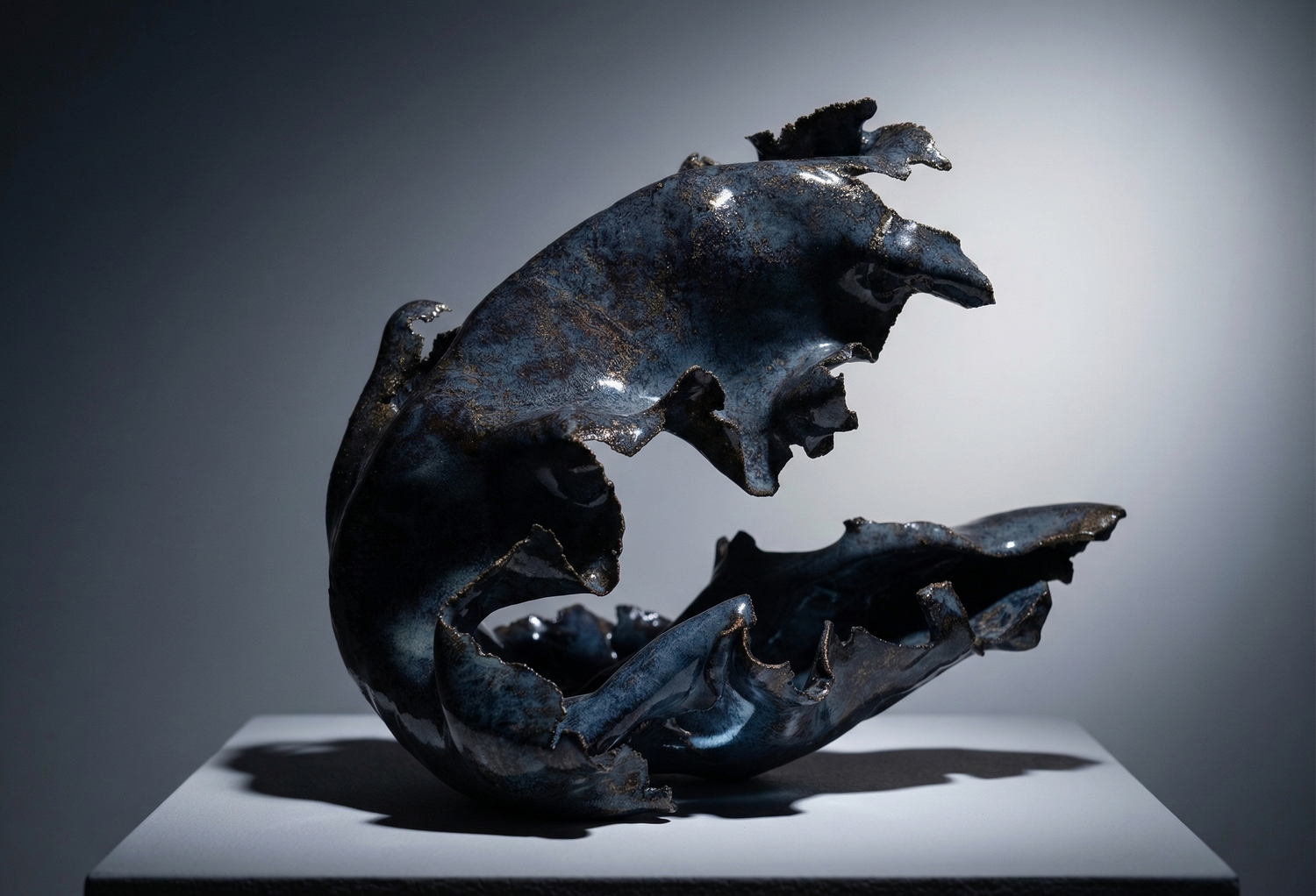 Blue sculpture on a grey pedestal against a grey background