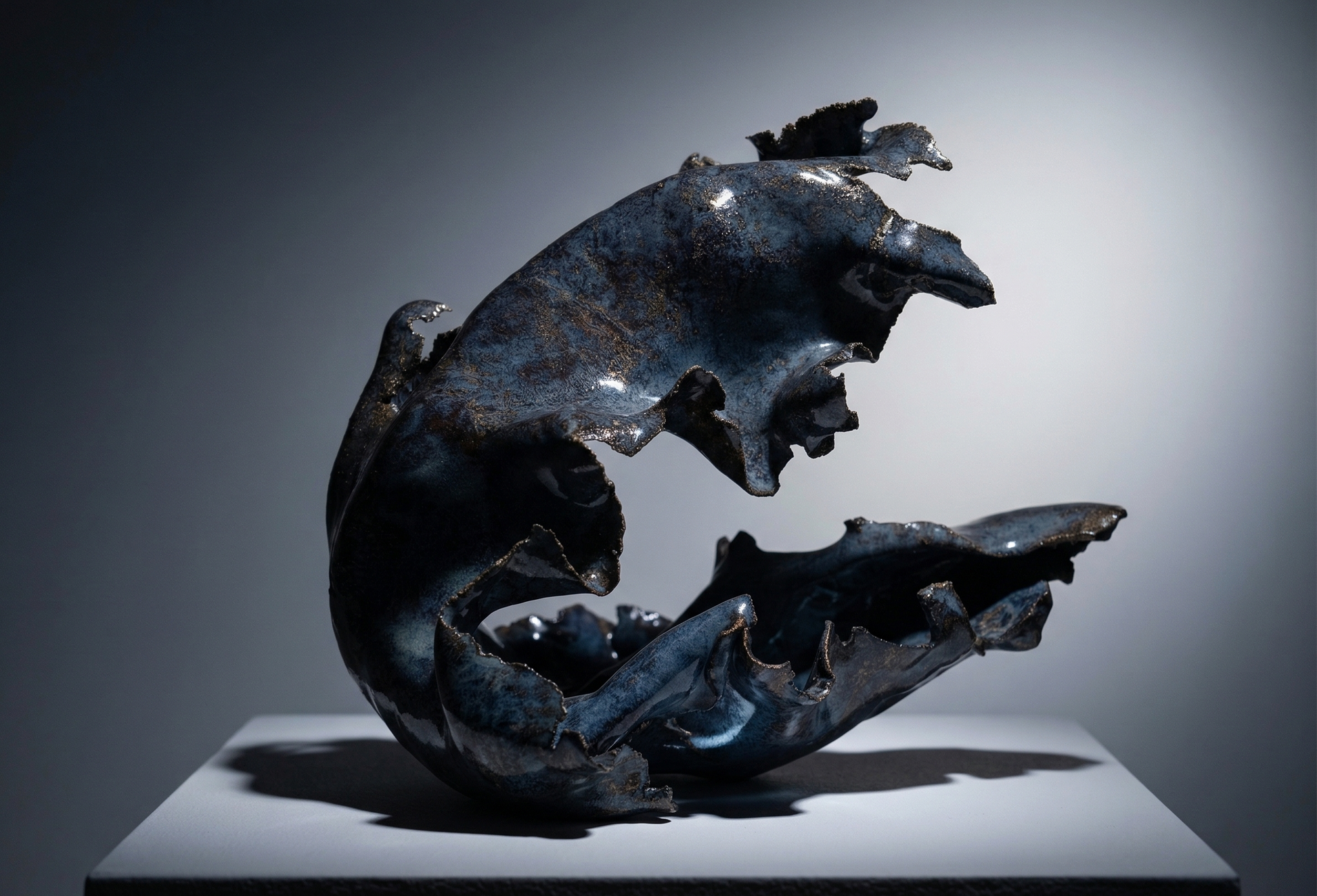 Blue sculpture on a grey pedestal against a grey background